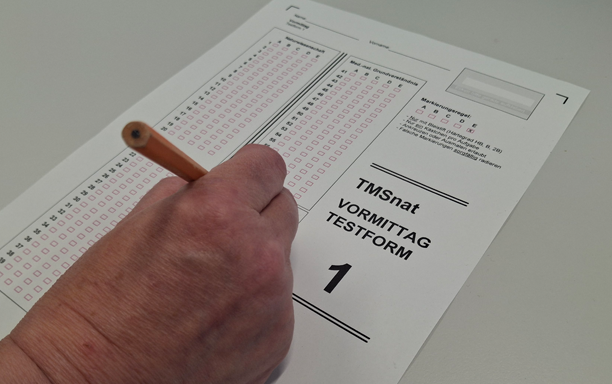 Blatt Papier als Antwortbogen, wo eine Hand mit einem Bleistift Markierungen macht